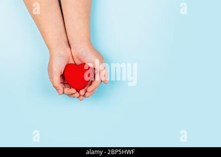 mains de petit enfant tenant le cœur rouge. Flat lay, vue de dessus. Concept de soins de santé, amour, bonté, Charité, don d'organes, généreux, plaisir Banque D'Images