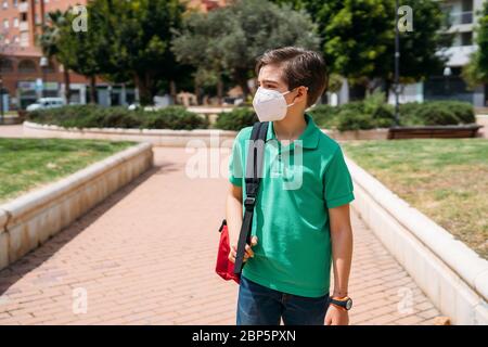 Garçon d'école avec masque pour se protéger pendant la pandémie du coronavirus Banque D'Images