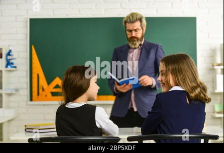 La vie scolaire quotidienne. Des amis étudient ensemble. Retour à l'école. Aide et assistance. Enseignant de niveau élémentaire. Groupe de discussion des enfants et des enseignants. Enseignant et enfants en classe. Dialogue et communication. Banque D'Images