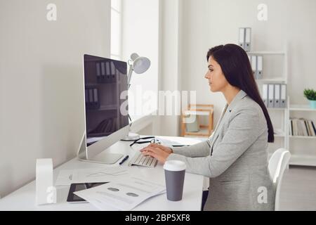 Travailler en ligne. Travail à distance dans les entreprises. Une femme d'affaires est assise à un ordinateur à la maison à l'intérieur. Banque D'Images