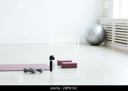 Image d'arrière-plan minimale du tapis de yoga et de l'équipement sportif sur le sol dans une salle blanche vide, espace de copie Banque D'Images