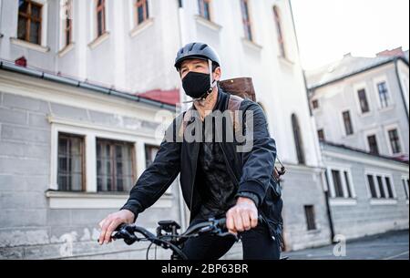 Livreur avec masque facial et vélo en ville. Banque D'Images