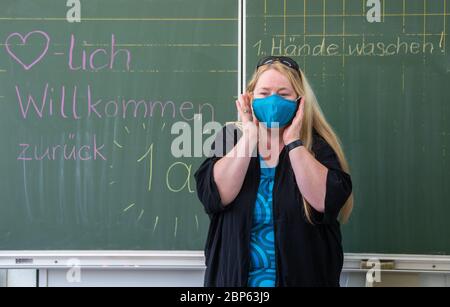 Dresde, Allemagne. 18 mai 2020. L'enseignante d'une première classe d'école primaire explique à ses élèves comment mettre et porter correctement un masque de protection de la bouche et du nez. À partir de ce lundi, les écoles primaires et secondaires ouvriront à nouveau leurs portes après des semaines de fermeture forcée en raison de la pandémie de Corona. Crédit : Robert Michael/dpa-Zentralbild/dpa/Alay Live News Banque D'Images