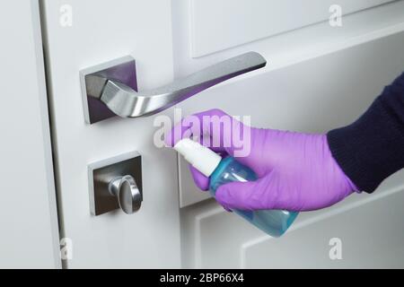 Lavage de la poignée de porte avec un assainisseur. COVID-19 Banque D'Images