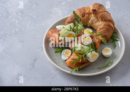 croissant avec saumon salé, concombre et œufs de caille Banque D'Images