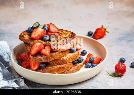 Toasts français traditionnels aux bleuets et aux fraises sur une assiette blanche. Banque D'Images