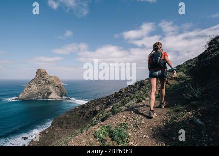 Femme traverse le pays sur un chemin en montagne à l'île des Canaries. Vue sur l'océan Banque D'Images