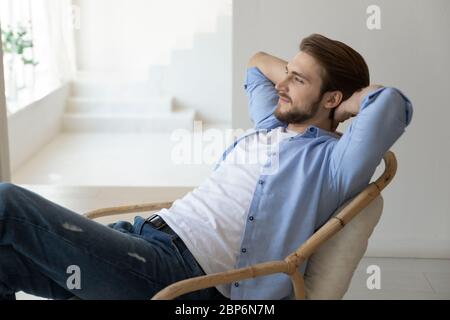 Un jeune homme souriant se détende dans la chaise de visualisation Banque D'Images