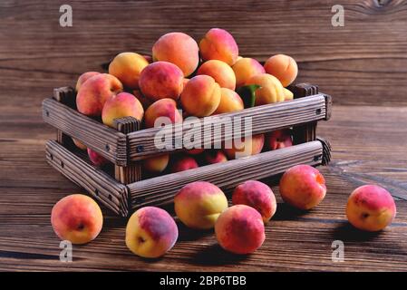 Abricots frais mûrs naturels dans une caisse en bois sur un fond en bois naturel gros plan Banque D'Images