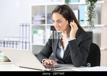 Une femme de télévendeur confuse regardant un ordinateur portable assis sur un bureau Banque D'Images