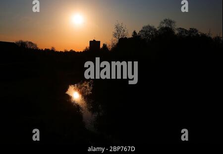 Lever de soleil sur Orangefield Park à Belfast, en Irlande du Nord, lors d'une chaude matinée de printemps avec un bloc d'appartements et de logements en arrière-plan. Banque D'Images