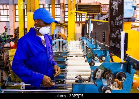 Johannesburg, Afrique du Sud - 16 octobre 2012 : ouvrier d'usine africain sur un métier à tisser de ligne de montage de trame de cobobineuse Banque D'Images