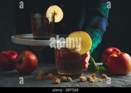Femelle avec plateau, verre de cidre. Composition avec cidre et pomme sur table grise Banque D'Images