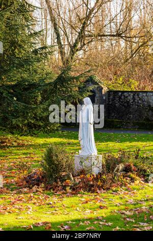 Une statue dans la promenade Rosaire au Prieuré d'Aylesford de notre Dame Marie parmi les feuilles d'automne lors d'un hiver ensoleillé, Kent, Royaume-Uni Banque D'Images