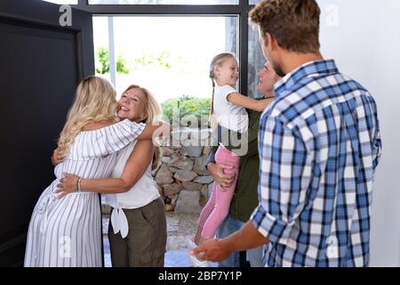 Famille caucasienne appréciant leur temps à la maison saluant un couple caucasien âgé Banque D'Images