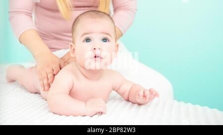 Massage pour bébé l'arrière-plan. Les jeunes donnant un thérapeute de massage du dos un bébé garçon. Banque D'Images