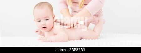 Massage pour bébé bannière. Les jeunes donnant un thérapeute de massage du dos un bébé garçon. Massage pour bébé concept sur fond blanc avec l'exemplaire de l'espace. Banque D'Images