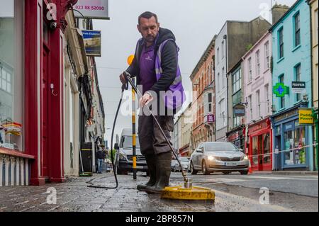 Bandon, West Cork, Irlande. 18 mai 2020. Ce matin, Bandon a eu son principal nettoyage en profondeur, dans le cadre de la phase de « retour aux affaires » de sortie du confinement de Covid-19, Soft Clean Group a été chargé d'effectuer la tâche à Bandon. Marcin Urbaniak, un employé, nettoie la rue en douceur. Crédit : AG News/Alay Live News Banque D'Images