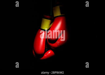 Boxers gants rouges. Équipement de sport professionnel isolé sur fond noir de studio. Concept de sport, leadership, compétition, mode de vie sain en mouvement et en action, entraînement. Gros plan, espace de copie. Banque D'Images