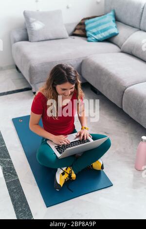 femme faisant du sport sur un tapis suivant des cours en ligne avec un ordinateur portable à la maison Banque D'Images