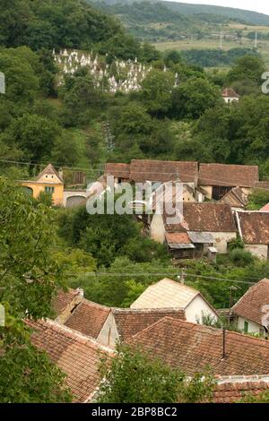 Vue sur un vieux village traditionnel saxon dans le pays de Sibiu, Transylvanie, Roumanie, et un cimetière sur la colline Banque D'Images