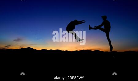 Silhouettes de deux hommes de combat sur fond de coucher de soleil. Banque D'Images