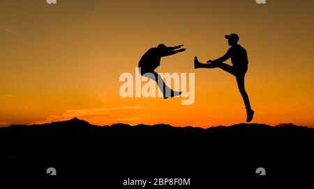 Silhouettes de deux hommes de combat sur fond de coucher de soleil. Banque D'Images