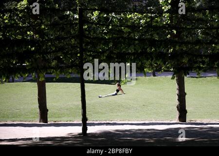 Bruxelles, Belgique. 18 mai 2020. Une femme bénéficie du soleil dans un parc à Bruxelles, Belgique, le 18 mai 2020. La Belgique est entrée lundi dans la phase 2 de la déconditionnement, les écoles ouvrant leurs cours à certains grades dans des conditions organisationnelles strictes. Crédit: Zhang Cheng/Xinhua/Alay Live News Banque D'Images