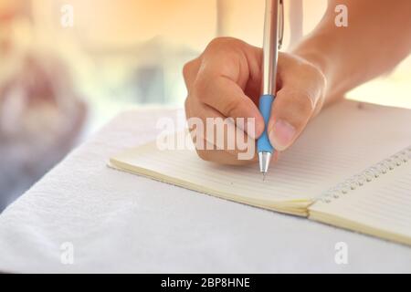 Gros plan de la main masculine avec écriture au stylo sur un ordinateur portable. Banque D'Images