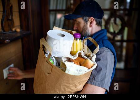 Homme de messagerie livrant des courses, frappant sur la porte. Banque D'Images