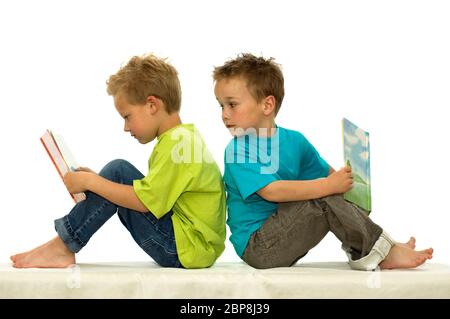 Deux amis lire un livre, un garçon à la surprise par le livre de l'autre. Banque D'Images