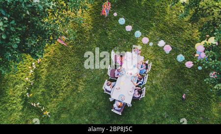 Vue aérienne des petits enfants assis à une table lors de la fête d'été dans le jardin. Banque D'Images