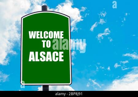 Panneau vert avec message de bienvenue BIENVENUE EN ALSACE, isolé sur fond ciel bleu clair avec espace de copie disponible. Concept de destination de voyage Banque D'Images