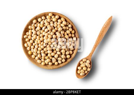 Vue de dessus des graines de soja dans une assiette en bois et dans une cuillère en bois sur un bacille blanc avec un passe-cheveux. Banque D'Images