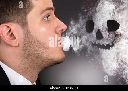 Close-up of a Man Smoking une forme de crâne formé Banque D'Images