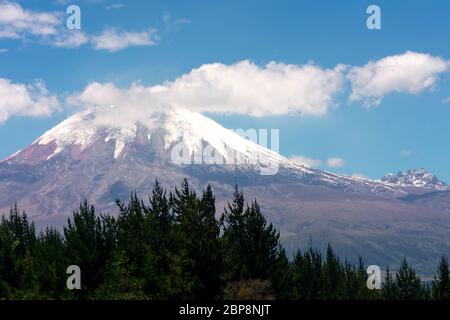 Volcan Cotopaxi en Equateur, ciel bleu avec peu de nuages derrière les montagnes un jour de printemps Banque D'Images