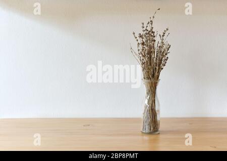 Bouquet de fleurs séchées en bouteille ou fleur sèche en pot sur table en bois avec fond mural avec la lumière dans la fenêtre du matin semble chaud et relaxant Banque D'Images