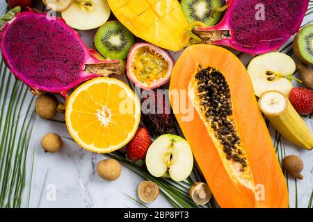 Assortiment de différents fruits exotiques tranchés avec des feuilles tropicales sur table. Vue de dessus. Prise de vue verticale. Mode de vie sain, nourriture, régime, vacances, résumé Banque D'Images