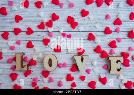 Le mot amour en lettres de bois sur fond de coeurs rouges, roses, blancs. Bonne Saint Valentin, Fête des mères, 8 mars, Journée mondiale de la femme. Banque D'Images