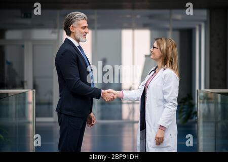 Médecin parlant au représentant commercial pharmaceutique, en serrant la main. Banque D'Images