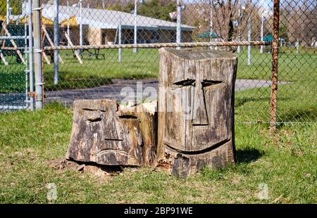 Deux souches d'arbre dans un parc sculpté avec un visage triste et heureux Banque D'Images