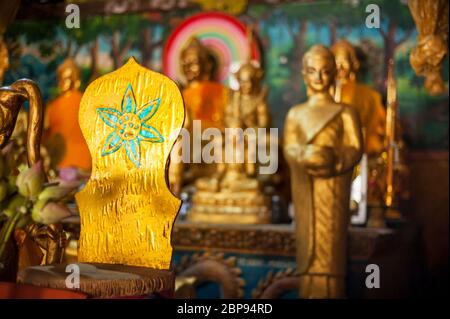 Fleur bleue sur une chaise avec statues de bouddha en arrière-plan à l'intérieur d'un temple. Oudong Mountain. Province de Kampong Speu, Cambodge, Asie du Sud-est Banque D'Images