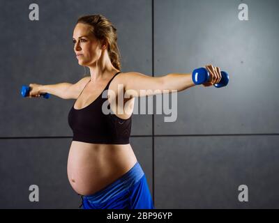 Photo d'une femme enceinte d'une trentaine d'exercices avec haltères. Banque D'Images