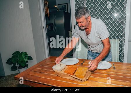 Homme servant le dîner de la nourriture indienne livrée par un restaurant. Récipients en plastique avec de délicieux aliments sur la table. Banque D'Images