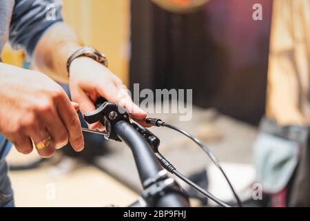 Mise en place de pauses d'un vélo, vue rapprochée. Mains humaines réparant un vélo dans un magasin de vélos local Banque D'Images