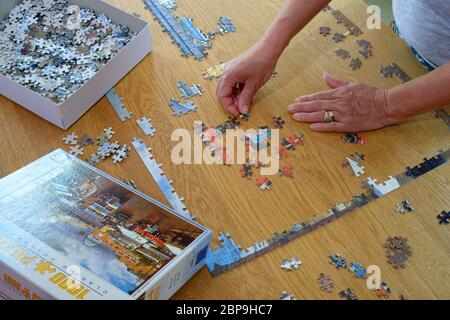 Puzzle en cours de remontage par une femme. Reportez-vous à l'image pour la main et la bordure presque terminée. Banque D'Images