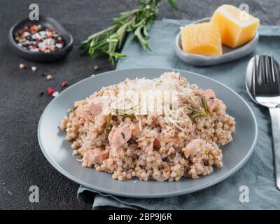 Le sarrasin cru risotto à la viande de poulet et fromage parmesan romarin servi en gris sur fond noir de la plaque de ciment. Des plats sans gluten et de sarrasin recette Banque D'Images