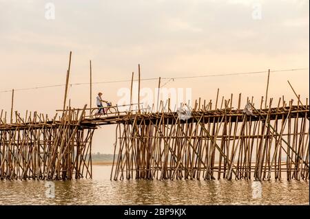 Un cycliste traverse un pont de bambou au-dessus du Mékong au coucher du soleil. Ko Pen, Cambodge, Asie du Sud-est Banque D'Images