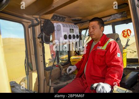 (200518) -- YULI, 18 mai 2020 (Xinhua) -- il Zhoumin, qui a participé à la construction de la deuxième autoroute à travers le désert de Taklimakan, conduit un bulldozer sur le site de construction d'une autoroute dans le désert de Taklimakan, dans la région autonome de Xinjiang, dans le nord-ouest de la Chine, le 16 mai 2020. La construction de l'autoroute Yuli-Qiemo, la troisième route nord-sud traversant le désert de Taklimakan, est entrée dans la ruée finale. Les travailleurs de China Communications Construction Company Ltd. Travaillent sur la plus grande dune de ce projet, avec un volume estimé de 1.2 millions de mètres cubes de sable à traiter. Banque D'Images