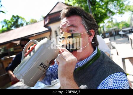 Munich. 18 mai 2020. Un homme lève son masque de bouche Koenig Ludwig pour prendre une bière dans une tasse. Réouverture du jardin de bière Paulaner sur Nockherberg au cours de la période de relâchement de la couronne le 18 mai 2020 à Munich. | utilisation dans le monde crédit : dpa/Alay Live News Banque D'Images